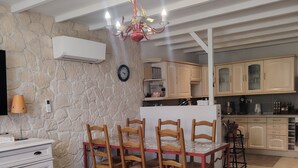 Un comedor con mesa y sillas, una cocina con armarios y una pared de piedra.