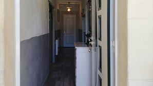 Un pasillo estrecho con suelo de madera, un armario blanco y una puerta a la derecha.