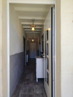A narrow hallway with a wooden floor, a white cabinet, and a door on the right. - Nice little house for visiting the little province and the Camargue. (Arles)