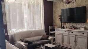 Una sala moderna con un sofá, una mesa de centro, un televisor y una pared de piedra.