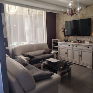 A modern living room with a sofa, coffee table, TV, and a stone wall. - Nice little house for visiting the little province and the Camargue. (Arles)