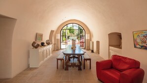 Uma área de refeições com uma mesa, bancos, um sofá vermelho e uma grande janela em arco.