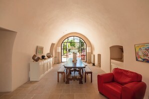Zona pranzo con tavolo, panche, un divano rosso e un'ampia finestra ad arco.