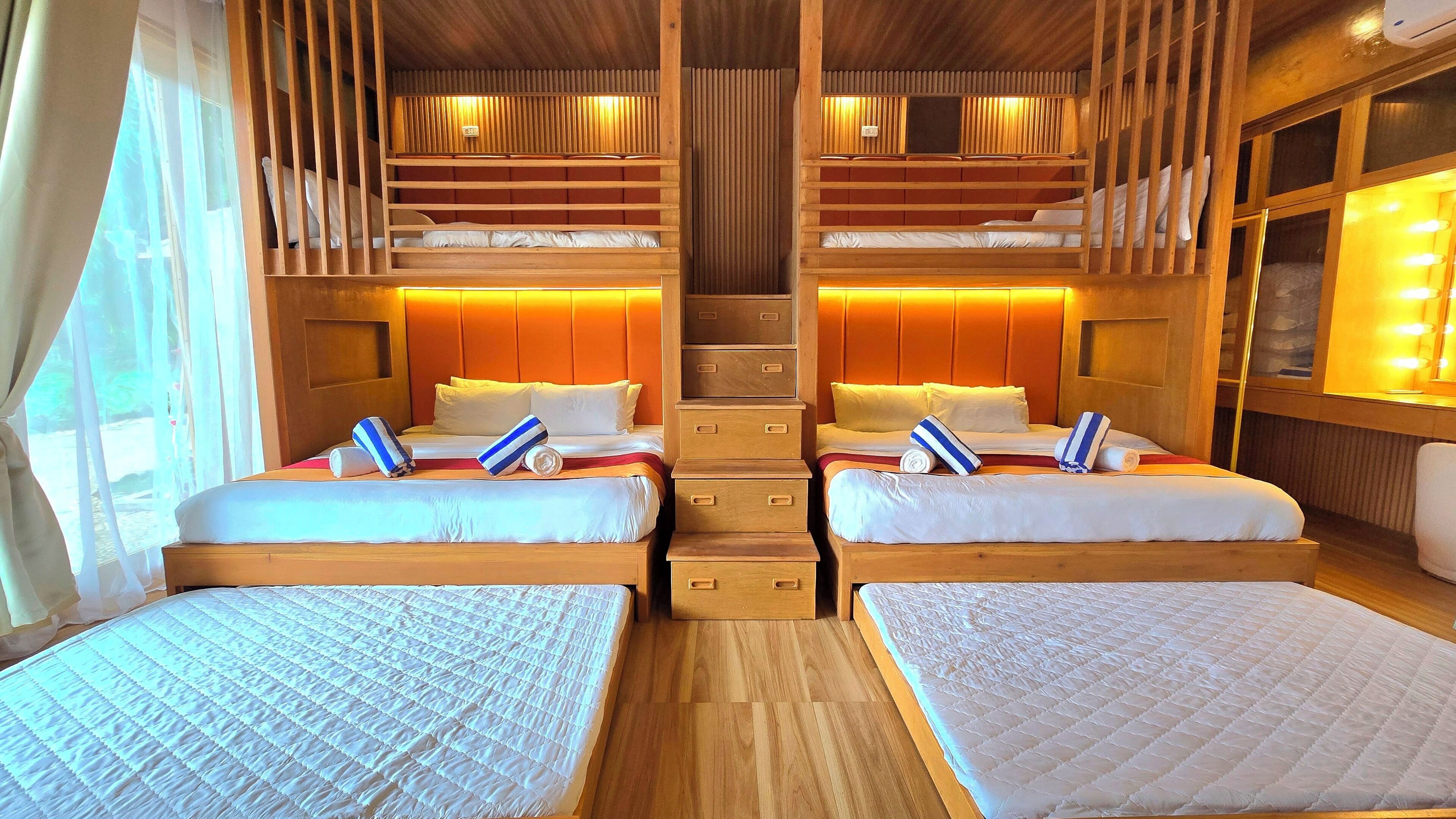 A cabin with two beds, a wooden ceiling, and a window with curtains.