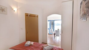 Une chambre à coucher avec un lit, une porte en bois et une vue sur un coin repas.