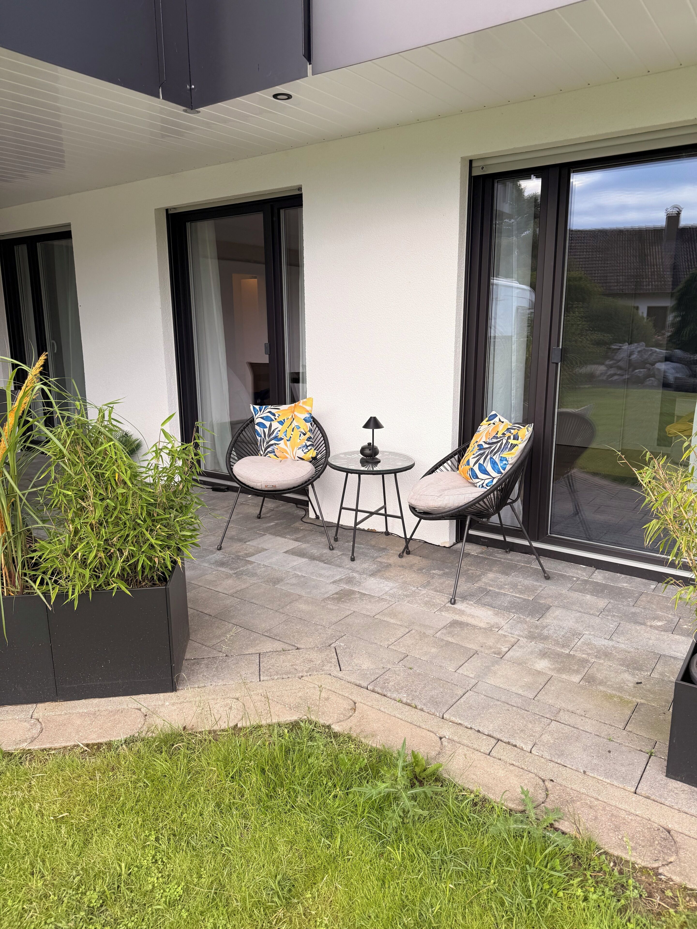 Eine Terrasse mit zwei Stühlen, einem kleinen Tisch und einem Blumentopf.