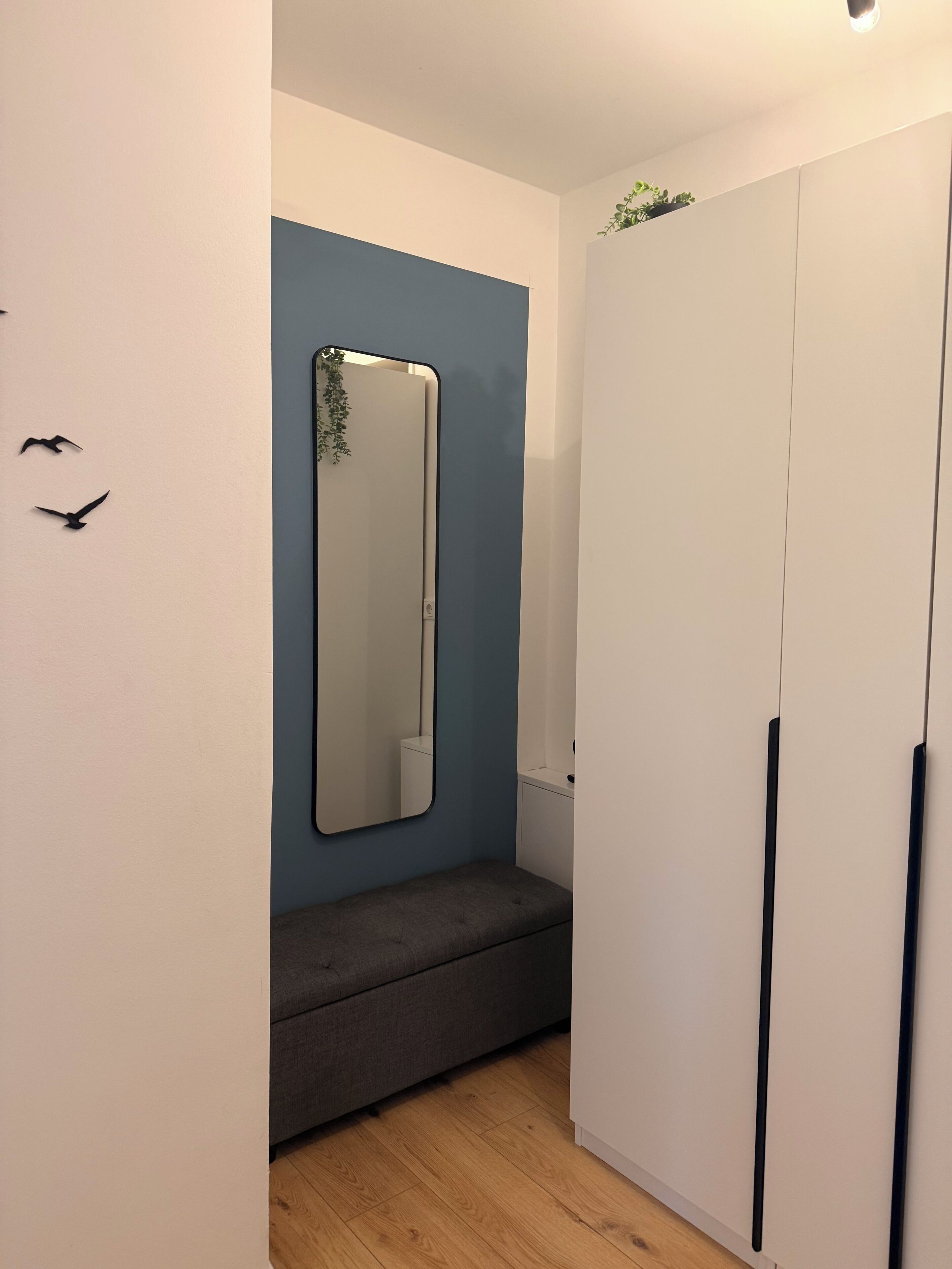 Een kamer met een bank, een grote spiegel en een kledingkast.