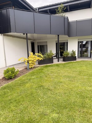 A modern building with a covered patio area, outdoor seating, and potted plants. - Lippe Loft (Lage)