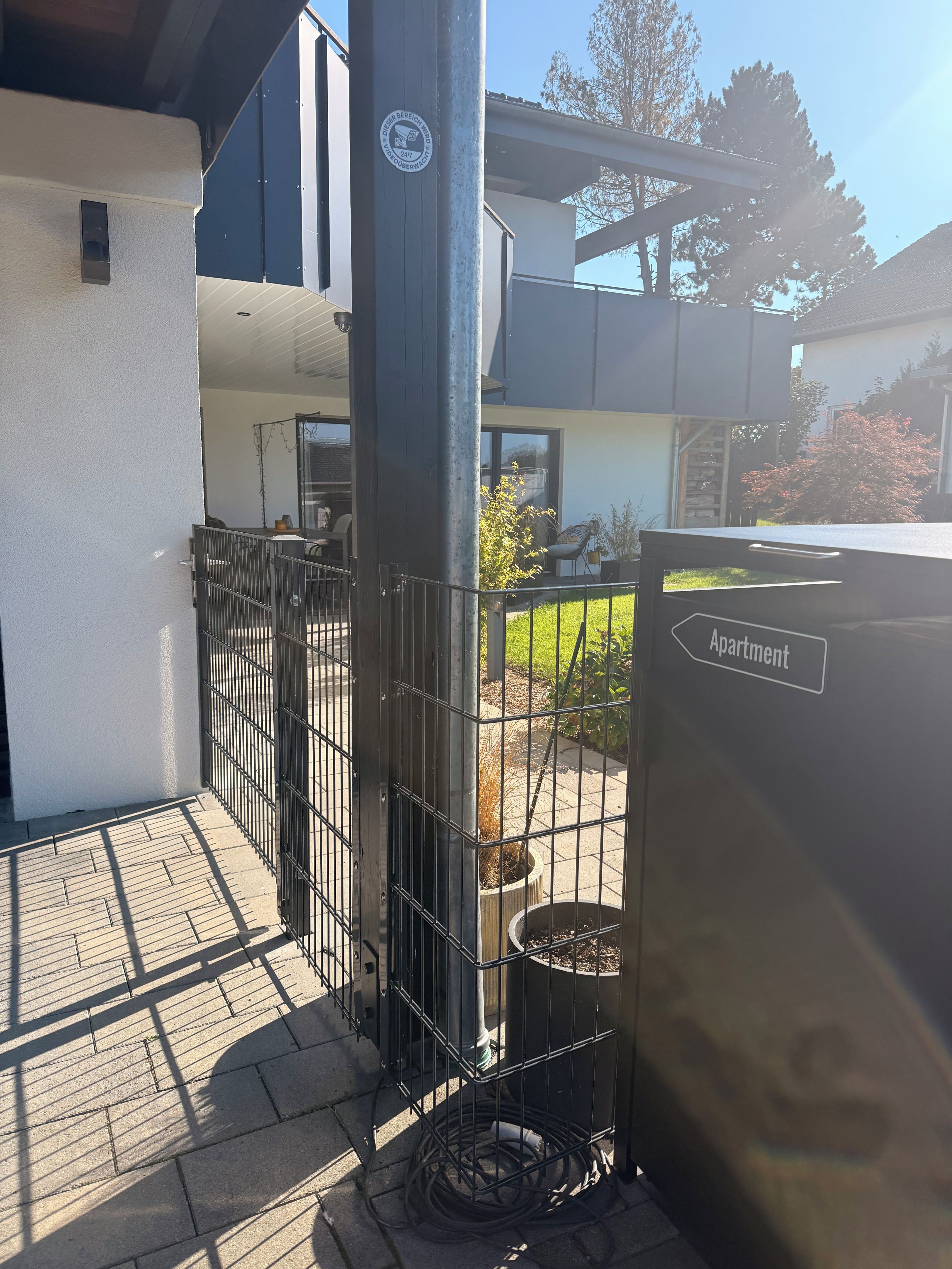 Un espacio al aire libre con una reja de metal, una planta en maceta y un letrero que indica un apartamento.