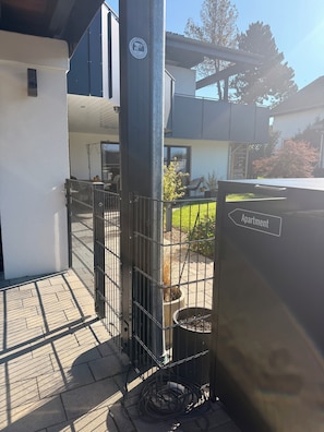 An outdoor area with a metal gate, a potted plant, and a sign indicating an apartment.