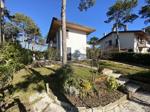 Ein modernes, zweistöckiges Haus mit gepflegtem Garten, Steinstufen und blauem Himmel.