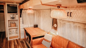 A cozy interior with a wooden table, a sofa, a TV, and a shelf with baskets.