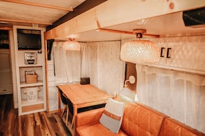 Ein gemĂŒtliches Interieur mit einem Holztisch, einer Couch, einem Fernseher und einem Regal mit Körben.