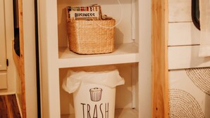 A white cabinet with a radio, a basket labeled 'BUSINESS,' and a trash can with a 'TRASH' label.