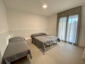 A room with two beds, a window with curtains, and a ceiling light. - Bright beachside apartment with two terraces (Bibione)