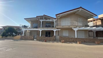 Una casa de dos pisos con balcón, paredes de piedra y cielo despejado.