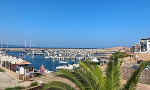 Ein Yachthafen mit angestaubten Booten, eine Steinmauer und ein klarer, blauer Himmel.