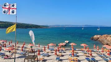 Une plage avec des parasols, des chaises longues et un drapeau.