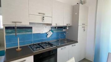 A modern kitchen with white cabinets, a blue backsplash, and a gas stove.