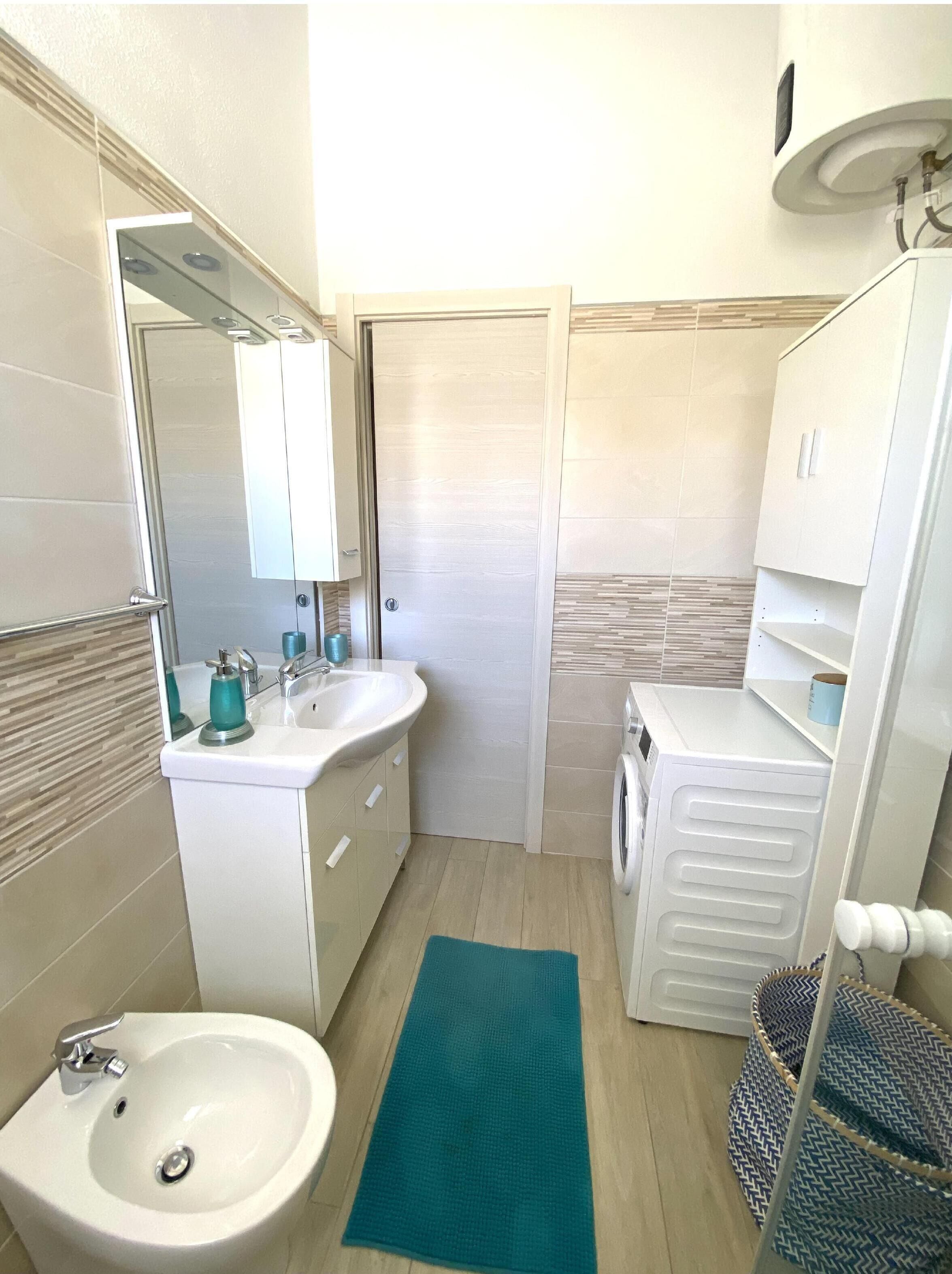 Baño pequeño con lavabo, espejo y lavadora.