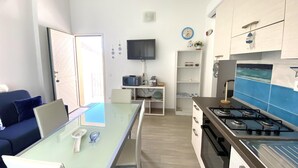 A compact kitchen with a gas stove, a microwave, and a TV on the wall. - Residence La Marina (Isola Rossa)