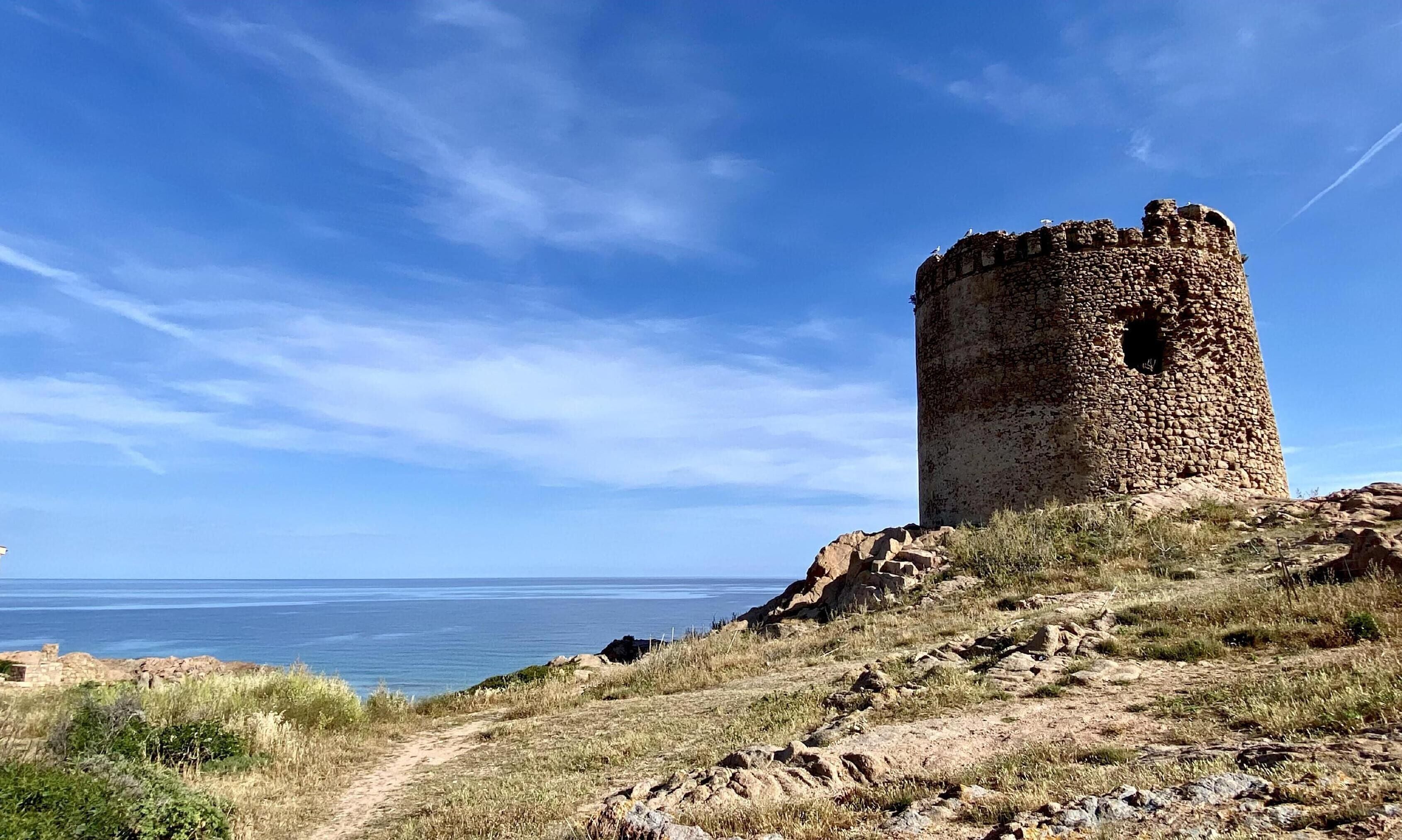 Une tour de pierre historique, située sur une falaise côtière, d’où l’on a une vue dégagée sur l’océan.