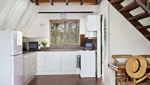 A kitchen with white cabinets, a microwave, and a window with blinds. - Beach Chalet - Unique Triangular Beach House (Mollymook Beach)