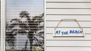 A window with horizontal blinds and a sign on the wall that reads 'AT THE BEACH'. - Beach Chalet - Unique Triangular Beach House (Mollymook Beach)