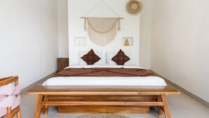 Una cama con estructura de madera, colchón blanco y almohadas marrones.