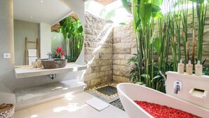 Un baño moderno con pared de piedra, una bañera grande y una zona de ducha.