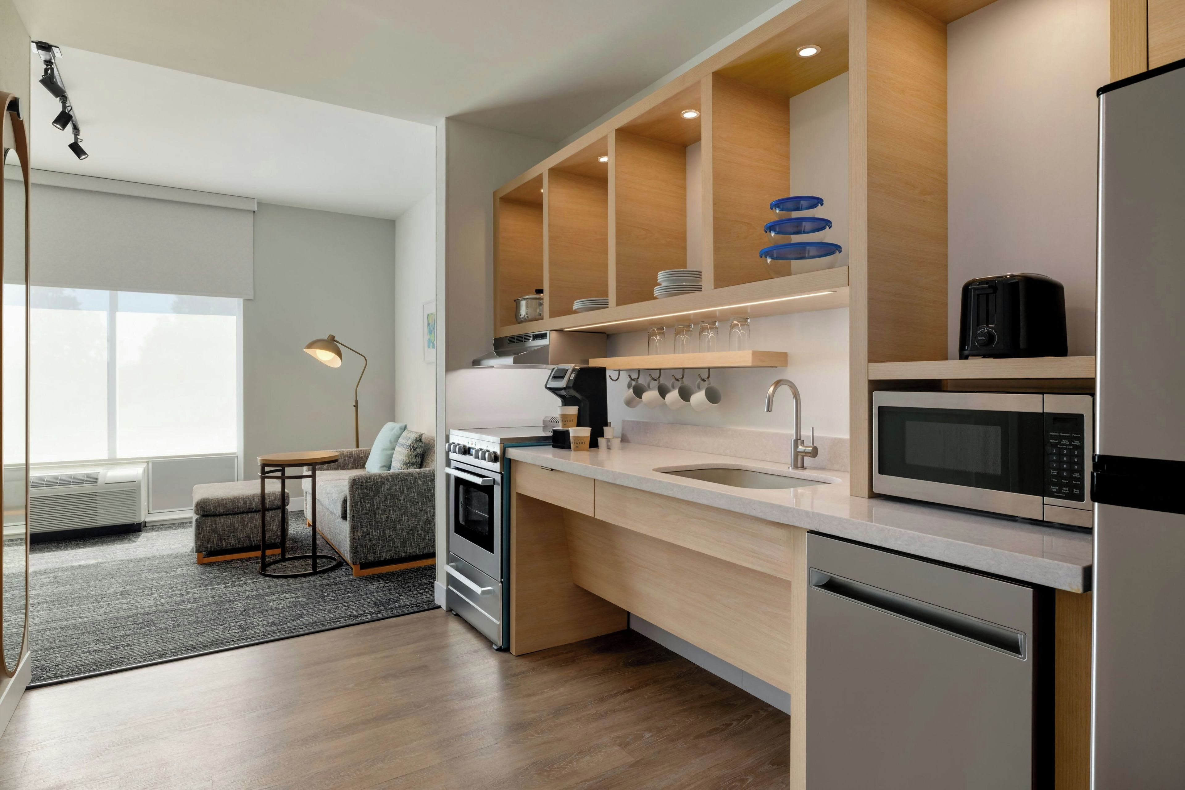 A modern kitchen with built-in appliances, a dining area with a sofa and table, and a view of the outdoors.