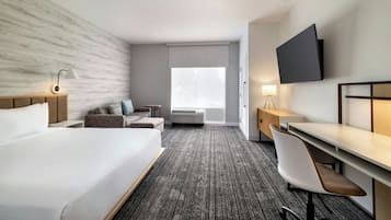Een hotelkamer met een groot bed, een bureau met stoel, een aan de muur bevestigde televisie en een raam met uitzicht.