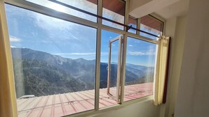 Una habitación con un ventanal grande, piso estampado y vistas a montañas.