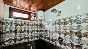 Un baño con un estampado floral en el suelo, techo de madera, una ventana y un ventilador.