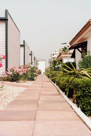 A pathway lined with plants and flowers, flanked by buildings with modern architecture. - Poseidon Beach Village Resort (San Salvo Marina)
