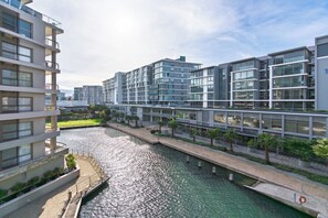 Ein modernes Gebäude mit mehreren Stockwerken, einem Wasserkanal und einem Fußgängerweg.
