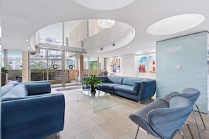 Eine moderne Lobby mit einem Glastisch, blauen Sofas und einer Rezeption.