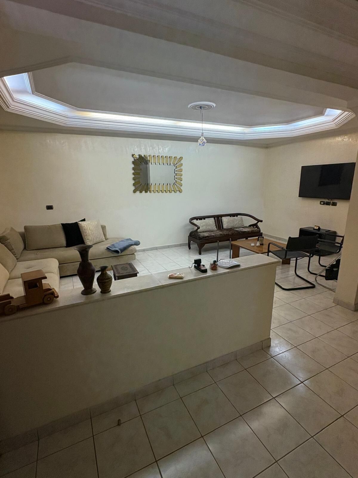 A living room with a central island, sofa, TV, and a ceiling skylight.