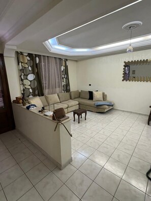 A modern living room with a sofa, a coffee table, and a small side table. - Bright 100m2 King balcony apartment (Mohammédia)