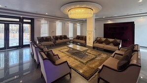 A spacious lobby with a central coffee table surrounded by sofas, a chandelier, and large windows. - Hotel Dekiling by Eastlynn Collections (Leh)