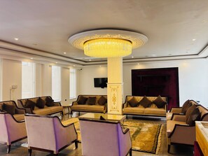 A well-lit lobby with a large chandelier, multiple sofas, armchairs, and a glass coffee table. - Hotel Dekiling by Eastlynn Collections (Leh)