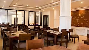 A dining area with tables and chairs, a large column, and a wall with a chalkboard. - Hotel Dekiling by Eastlynn Collections (Leh)