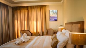A hotel room with a bed, a chair, a lamp, and a painting on the wall. - Hotel Dekiling by Eastlynn Collections (Leh)