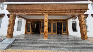 A building with a traditional architectural style, featuring ornate wooden columns and a set of stairs leading to a doorway with glass panels. - Hotel Dekiling by Eastlynn Collections (Leh)