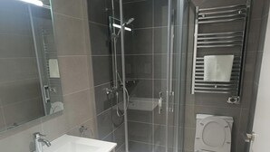 A modern bathroom with a glass-enclosed shower, a white sink, and a toilet. - Budget VictoryS Ensuite Room (Gibraltar)