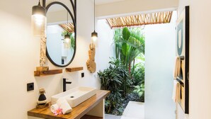 A modern bathroom with a wooden vanity, a large mirror, and a view of a tropical garden. - Infinity Villa by Tasvan (Badung)