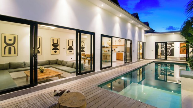 A modern house with a swimming pool, a wooden deck, and a living area with a sofa and coffee table. - Infinity Villa by Tasvan (Badung)