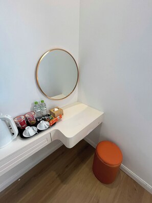 A bathroom with a white sink, a round mirror with a gold frame, a wooden tissue box, and a small orange stool. - Hub Multi 3 Hotel (Phu Quoc)
