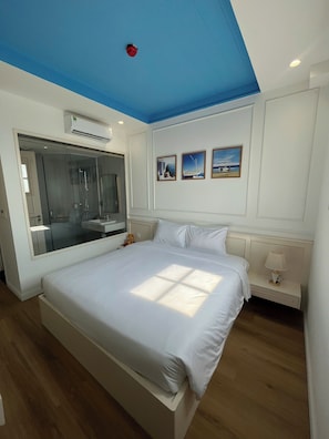A bedroom with a large bed, a glass shower enclosure, and three framed pictures on the wall. - Hub Multi 3 Hotel (Phu Quoc)