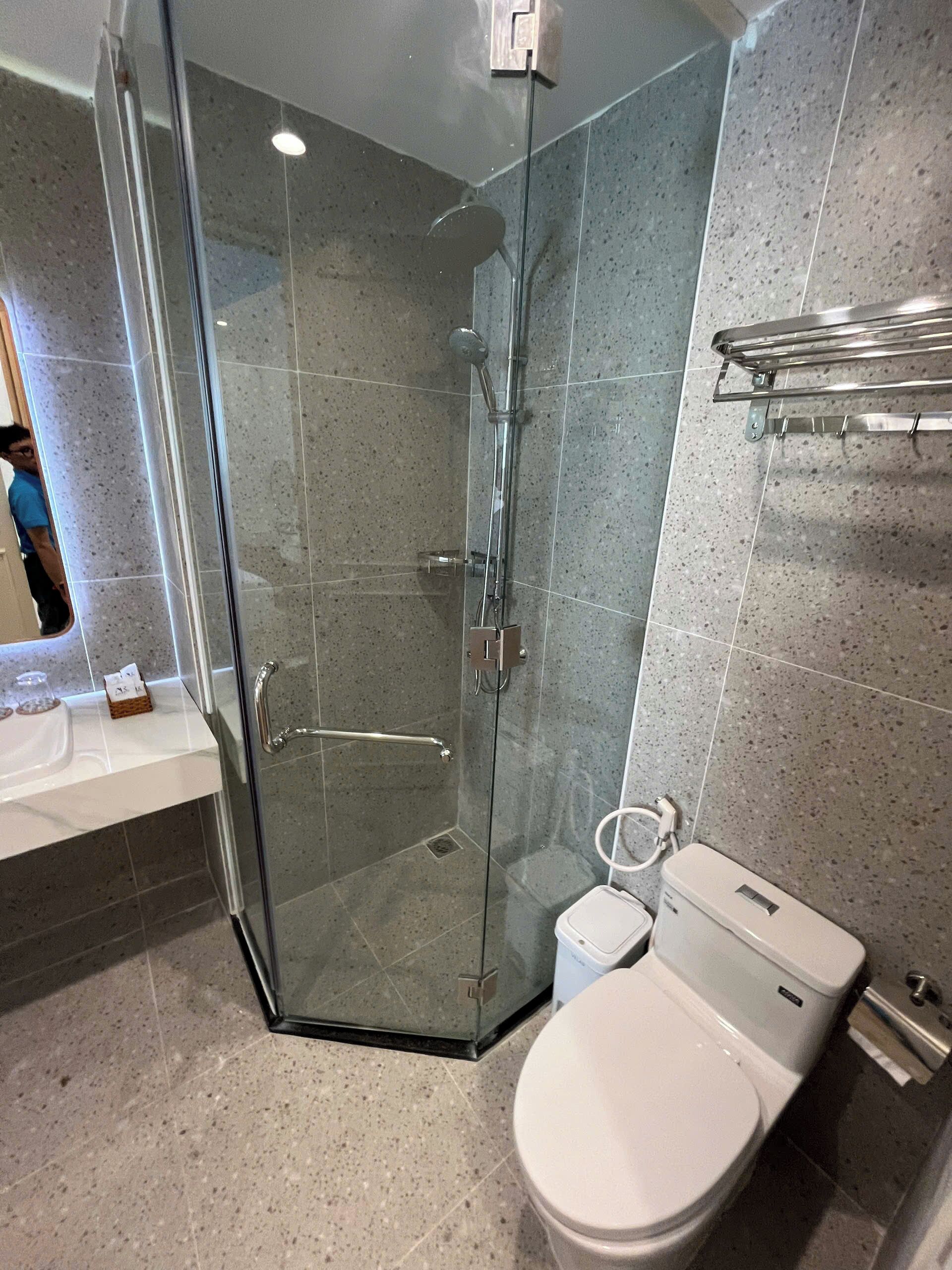 A modern bathroom with a glass-enclosed shower, a white toilet, and a vanity with a mirror.